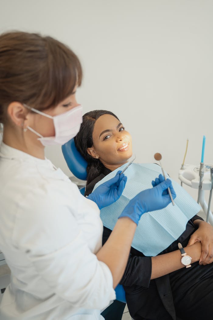 A dentist in protective gear attends a smiling patient in a modern clinic.